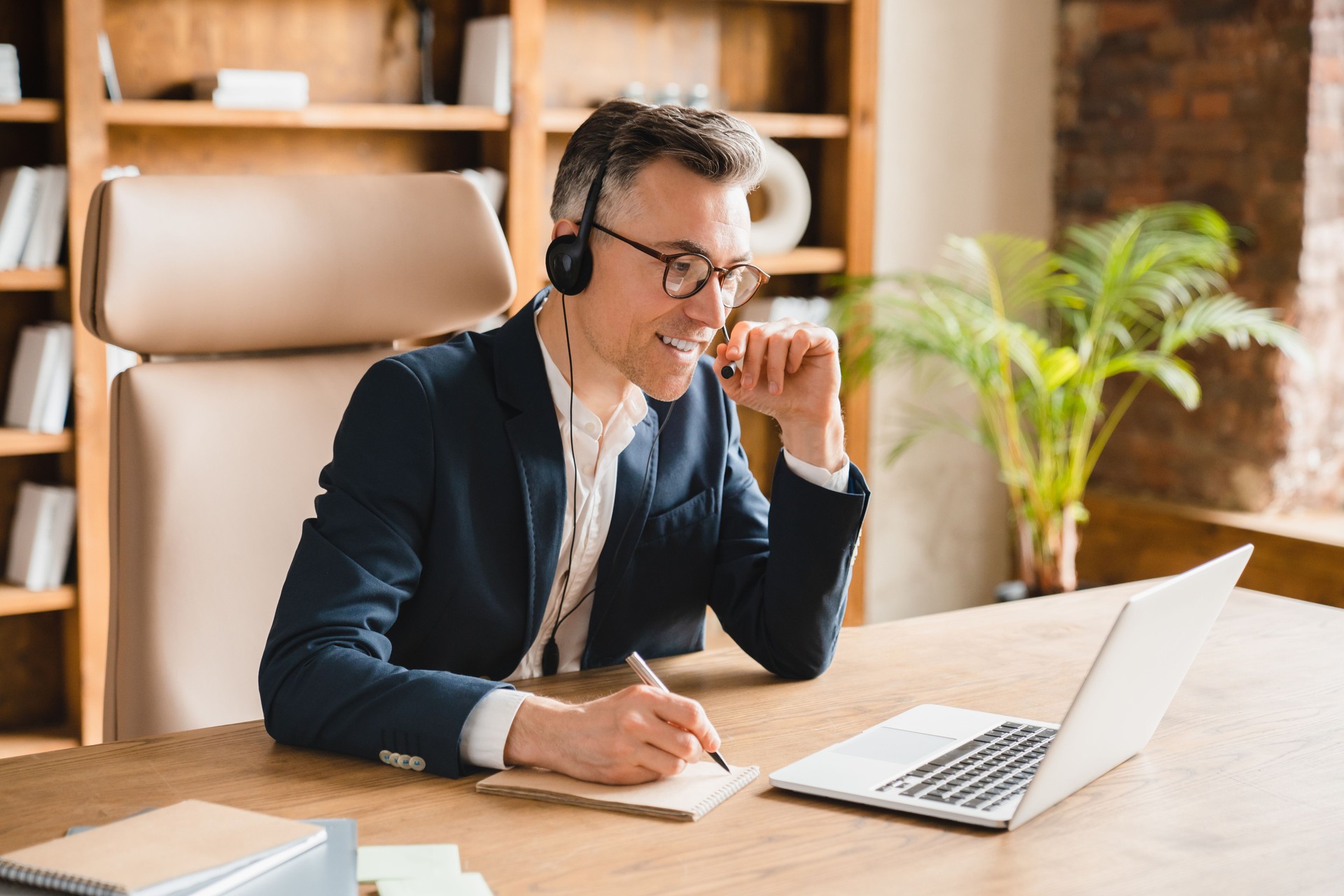 E-learning, distant education. Caucasian middle-aged mature businessman ceo boss freelancer teacher psychologist writing, taking notes while on online lesson session videocall in office